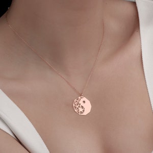 May include: A rose gold necklace with a geometric yin yang pendant.