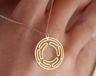May include: A gold-colored pendant necklace featuring a circular design with an open, geometric pattern. The necklace is suspended from a delicate chain. The pendant's design is a series of curved lines within a circle.