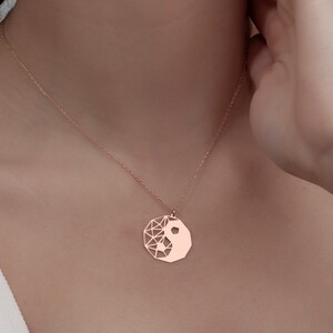 May include: A rose gold necklace with a geometric yin yang pendant.