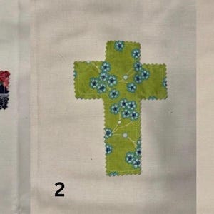 May include: Three fabric crosses with decorative edges are shown on a white background. The crosses are numbered 1, 2, and 3. Cross 1 is navy blue with red floral patterns. Cross 2 is green with blue floral patterns. Cross 3 is blue and white gingham.