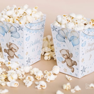 Peut inclure: Deux boîtes à popcorn bleues et blanches avec un motif d'ours en peluche. Une boîte dit "Bobby a 2 ans" et l'autre dit "Joyeux anniversaire ! 2".