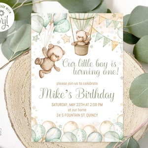 May include: A white invitation card with a green and brown teddy bear in a hot air balloon. The card says "Our little boy is turning one!" and "Mike's Birthday". The invitation is for a birthday party on Saturday, May 22nd at 2:00 PM at 24 S Fountain St, Quincy.