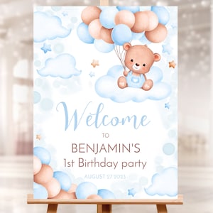 May include: Welcome to Benjamin's 1st Birthday party, a blue and brown watercolor illustration with a teddy bear holding balloons, clouds, and stars.