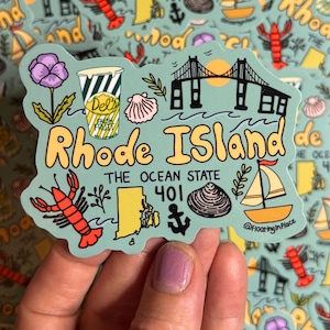 Op de afbeelding: Een sticker met een tealkleurige omtrek van Rhode Island met illustraties van een kreeft, zeilboot, brug en Del's Lemonade. De tekst luidt "Rhode Island" en "The Ocean State" met het kengetal "401".