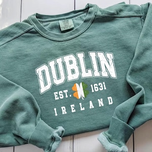 Peut inclure: Un sweat-shirt vert avec le texte "DUBLIN EST. 1631 IRLANDE" et un tr&egrave;fle &agrave; trois feuilles.