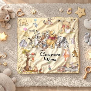 May include: A yellow baby blanket featuring illustrations of Winnie the Pooh and friends, with the text "Custom Name". The blanket is surrounded by baby toys, including a teddy bear, star-shaped lights, and wooden rattles.
