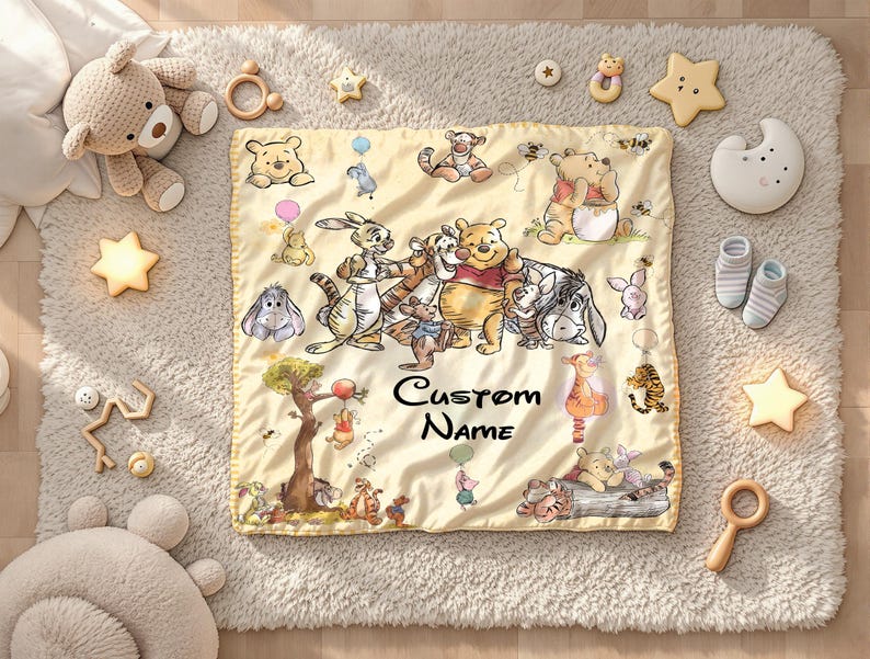 May include: A yellow baby blanket featuring illustrations of Winnie the Pooh and friends, with the text "Custom Name". The blanket is surrounded by baby toys, including a teddy bear, star-shaped lights, and wooden rattles.
