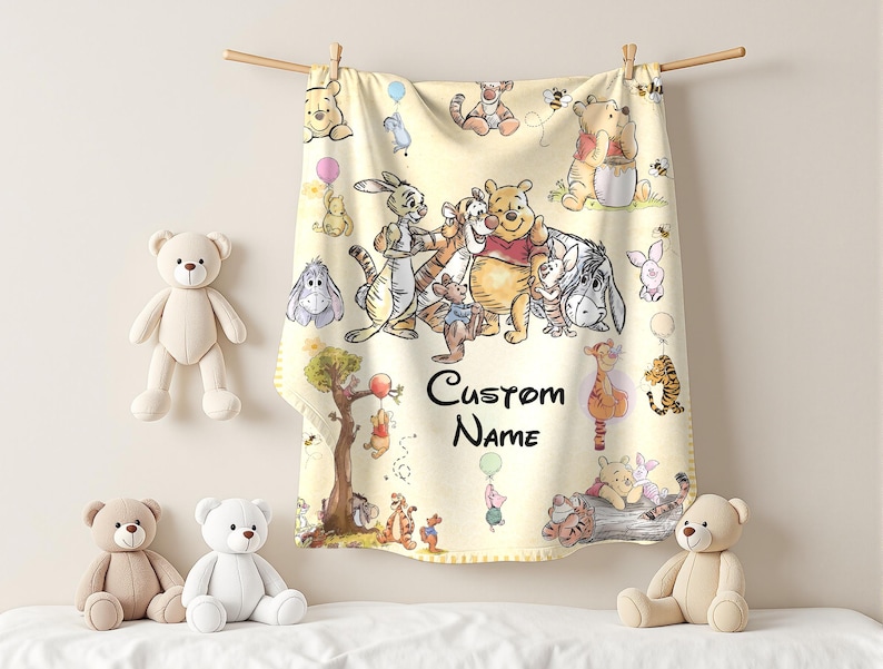 May include: A light yellow baby blanket featuring illustrations of Winnie the Pooh and friends. The blanket is hanging from a wooden rod with clothespins. The words "Custom Name" are printed on the blanket. Several teddy bears are in the image.