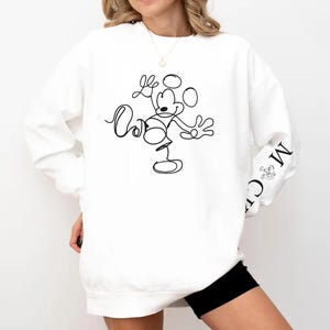 Puede incluir: Sudadera blanca con un dibujo de l&iacute;nea negra de Mickey Mouse en la parte delantera. El texto "Mickey" est&aacute; escrito en la manga.