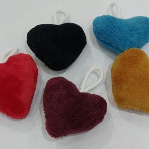 Könnte beinhalten: Fünf Plüschkissen in Herzform in verschiedenen Farben: Rot, Schwarz, Blau, Braun und Burgunderrot. Jedes Kissen hat eine weiße Schlaufe zum Aufhängen.