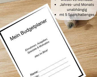 May include: A white budget planner with black text, including "Mein Budgetplaner" and lines for name, year, and motto. The planner is on a wooden surface. Text in the image says it is a digital download in A4/A5, PDF, reusable, and has 5 savings challenges.