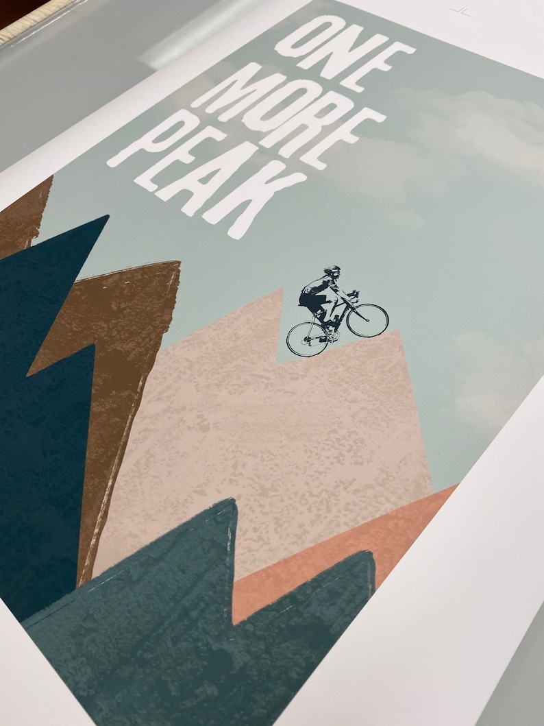 May include: A motivational poster with a cyclist riding up a mountain with the text "ONE MORE PEAK" in white letters on a light blue background.