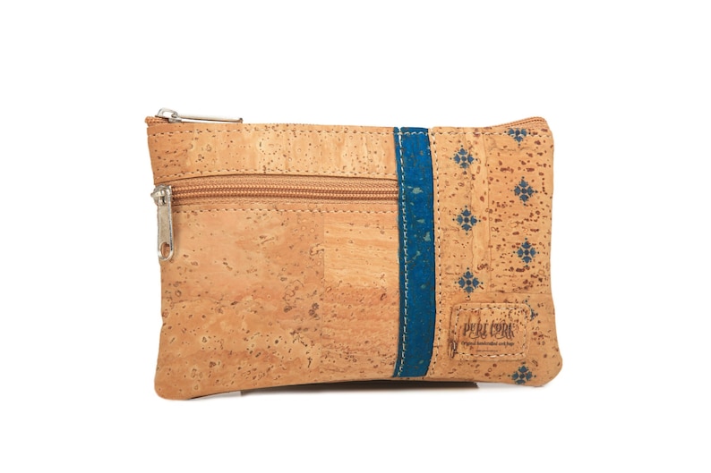 May include: A small, brown cork zippered pouch with a blue patterned fabric strip and a blue zipper pull. The pouch has a cork label that reads "Peli Cork - handcrafted with cork".