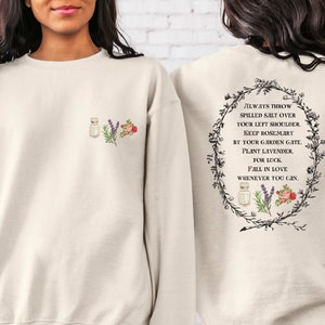May include: A cream-colored sweatshirt with a floral design and the text "ALWAYS THROW SPILLED SALT OVER YOUR LEFT SHOULDER. KEEP ROSEMARY BY YOUR GARDEN GATE. PLANT LAVENDER. FOR LUCK. FALL IN LOVE WHENEVER YOU CAN." on the back.