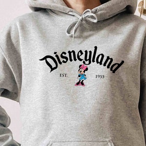 May include: A gray hooded sweatshirt with a black Disneyland logo and a small image of Minnie Mouse. The text "EST. 1955" is printed below the logo.