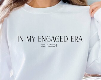 May include: White sweatshirt with the text "IN MY ENGAGED ERA" and the date "02.14.2024" printed on the front.