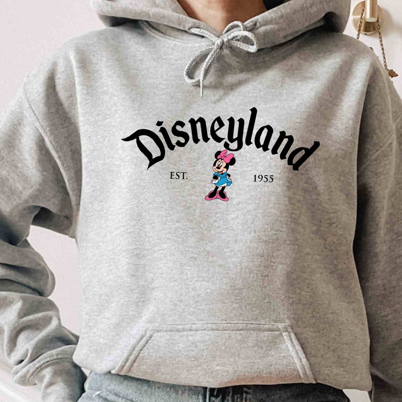 May include: A gray hooded sweatshirt with a black Disneyland logo and a small image of Minnie Mouse. The text "EST. 1955" is printed below the logo.