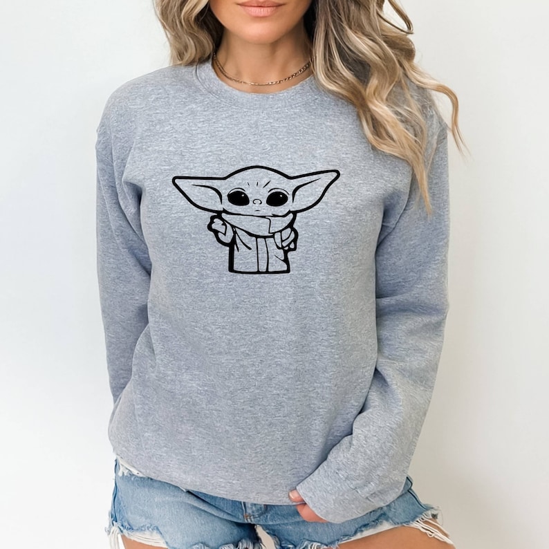 May include: A gray sweatshirt with a black outline of a character from the Star Wars franchise, known as "The Child" or "Baby Yoda", on the front.