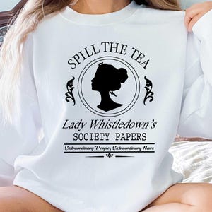 May include: White sweatshirt with the text "Spill the Tea" above a black silhouette of a woman's profile in a circle. Below the circle is the text "Lady Whistledown's Society Papers" and "Extraordinary People, Extraordinary News".