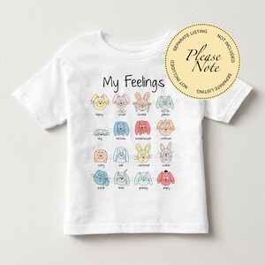 May include: White t-shirt with the text "My Feelings" printed on the front. The shirt features a grid of 16 colorful cartoon animals with different facial expressions, each labeled with a corresponding emotion.