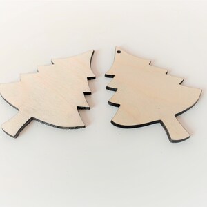May include: Two unfinished wooden Christmas tree decorations. The decorations are shaped like a traditional Christmas tree with a pointed top and a wide base. The decorations are made of light-coloured wood and have a smooth surface.