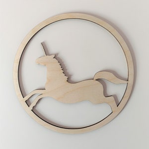 May include: A wooden cutout of a unicorn running in a circle. The unicorn is a silhouette with a simple design.