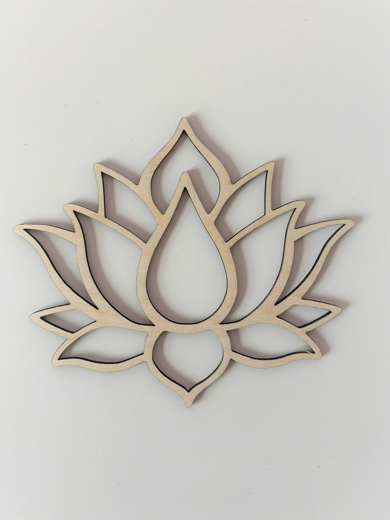 May include: A wooden cutout of a lotus flower with intricate details. The flower is light brown and has a delicate, symmetrical design.