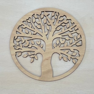 Könnte beinhalten: Eine runde Holz-Wanddekoration mit einem ausgeschnittenen Design eines Lebensbaums mit filigranen Ästen und Blättern.