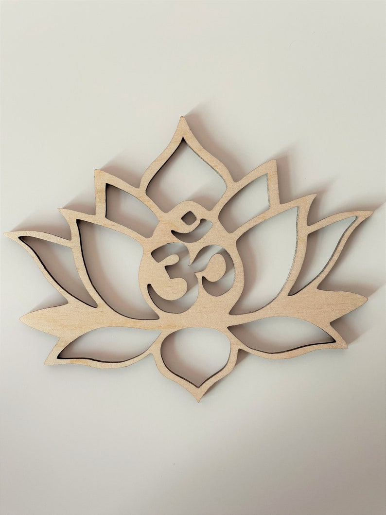 May include: A wooden cutout of a lotus flower with an Om symbol in the center. The flower is light brown and has a detailed design.