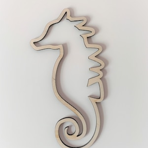 May include: A wooden cutout of a seahorse. The cutout is a simple outline of the seahorse with a detailed fin and tail.