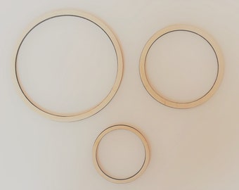 May include: Three wooden hoops of different sizes, arranged in a triangular pattern on a white background.