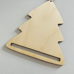 May include: A wooden Christmas tree ornament with a star on top. The ornament has a slot cut out of the bottom for hanging.