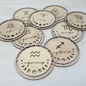 May include: Twelve wooden zodiac signs with the astrological symbols and names. The signs are arranged in a circle with the names facing outwards.