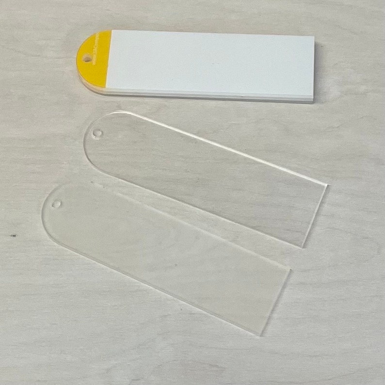 May include: Two clear acrylic bookmarks with rounded edges and a hole at the top. A white bookmark with a yellow top is also included.