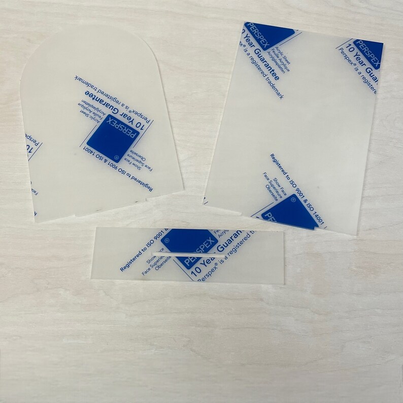 K&ouml;nnte beinhalten: Vier transparente Plastikplatten mit dem Text "Perspex&reg; 10 Year Guarantee" und "Registered to ISO 9001 & ISO 14001" darauf gedruckt. Perspex&reg; ist eine eingetragene Marke.