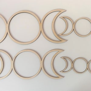 Peut inclure: Trois ensembles de décoration murale en bois en forme de triple lune de déesse de différentes tailles. La décoration est en bois brut et présente trois croissants de lune et un cercle au centre.
