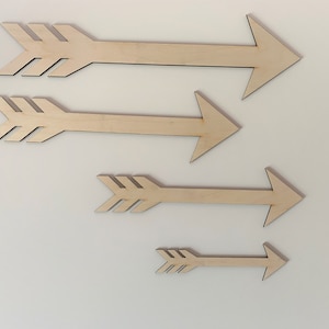 May include: Four wooden arrows of varying sizes, all pointing to the right. The arrows are made of natural wood and have a simple, rustic design.