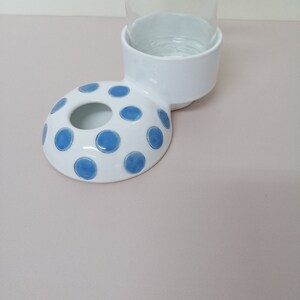 May include: White ceramic pet bowl with blue polka dots and a matching stand for a water bottle.