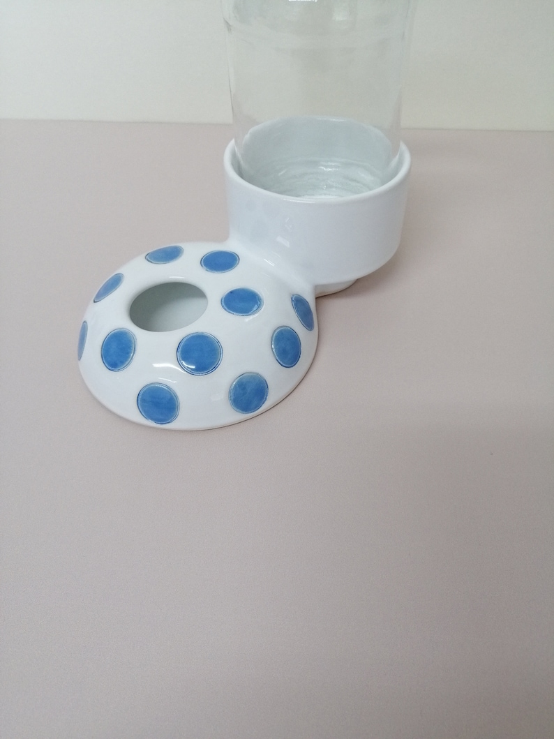 May include: White ceramic pet bowl with blue polka dots and a matching stand for a water bottle.