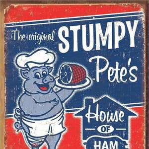 May include: A vintage-style metal sign advertising "Stumpy Pete's House of Ham." The sign features a cartoon pig wearing a chef's hat and holding a platter of ham. The text on the sign reads "The original Stumpy Pete's House of Ham - If you dig on swine, try some of mine!"