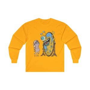 Op de afbeelding: Een geel longsleeve t-shirt met een afbeelding van een monster met meerdere ogen dat in een spiegel kijkt. Het monster glimlacht en heeft een verraste uitdrukking. Een kleiner, bruin wezen staat links van de spiegel en kijkt naar het monster.