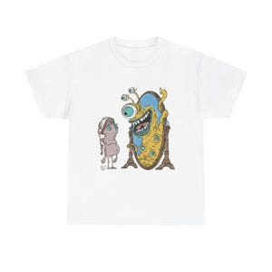Op de afbeelding: Een wit T-shirt met een afbeelding van een geel monster met meerdere ogen dat in een spiegel kijkt. Het monster glimlacht en heeft een blauwe en witte achtergrond. Een kleiner, roze monster met een blauwe hoed staat links van de spiegel.