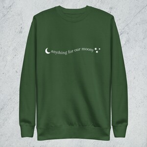 May include: A dark green sweatshirt with a white crescent moon and stars graphic. The text "anything for our moony" is printed on the sweatshirt.