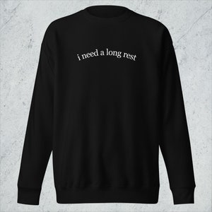 May include: Black sweatshirt with the text "i need a long rest" in white.