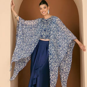 May include: A two-piece outfit comprising a blue floral print cape top and a high-waisted, navy blue skirt. The cape top has a delicate, flowing design, while the skirt has a layered, asymmetrical detail. The outfit is suitable for formal events.