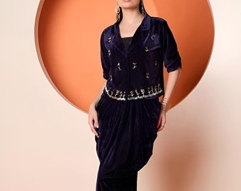 Op de afbeelding: Een donkerblauw fluwelen jasje met gouden versieringen en een bijpassende rok. Het jasje heeft een kraag en een knoopsluiting. De rok is in dhoti-stijl met plooien.