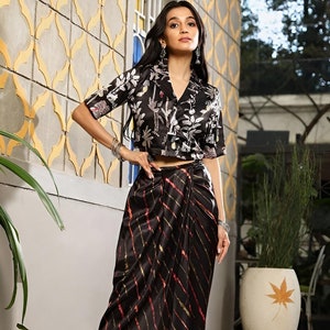 May include: A black and white floral print crop top with a collar and a black and gold striped skirt with a tie waist.