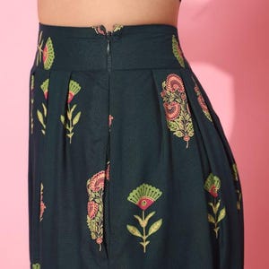 May include: A dark green skirt with a floral print. The skirt has a zipper closure in the back and pleats in the front.