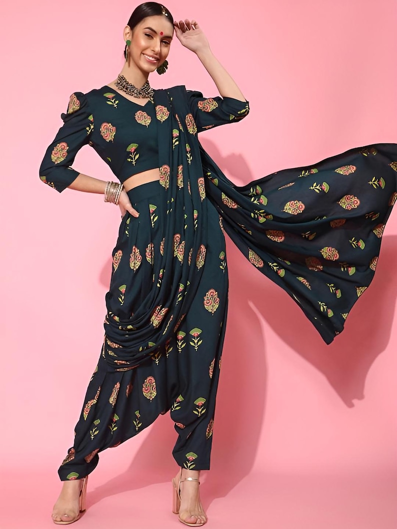 May include: A teal blue printed dhoti pant and crop top set with a matching printed dupatta. The outfit features a floral print in shades of pink, green, and gold.
