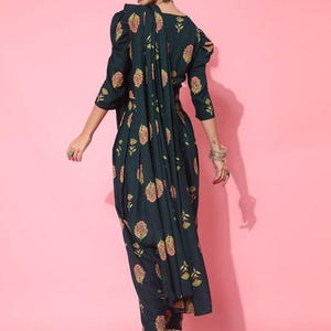May include: A dark green printed dress with a floral pattern. The dress has a gathered skirt and a fitted bodice. The dress is worn with a matching printed dupatta.